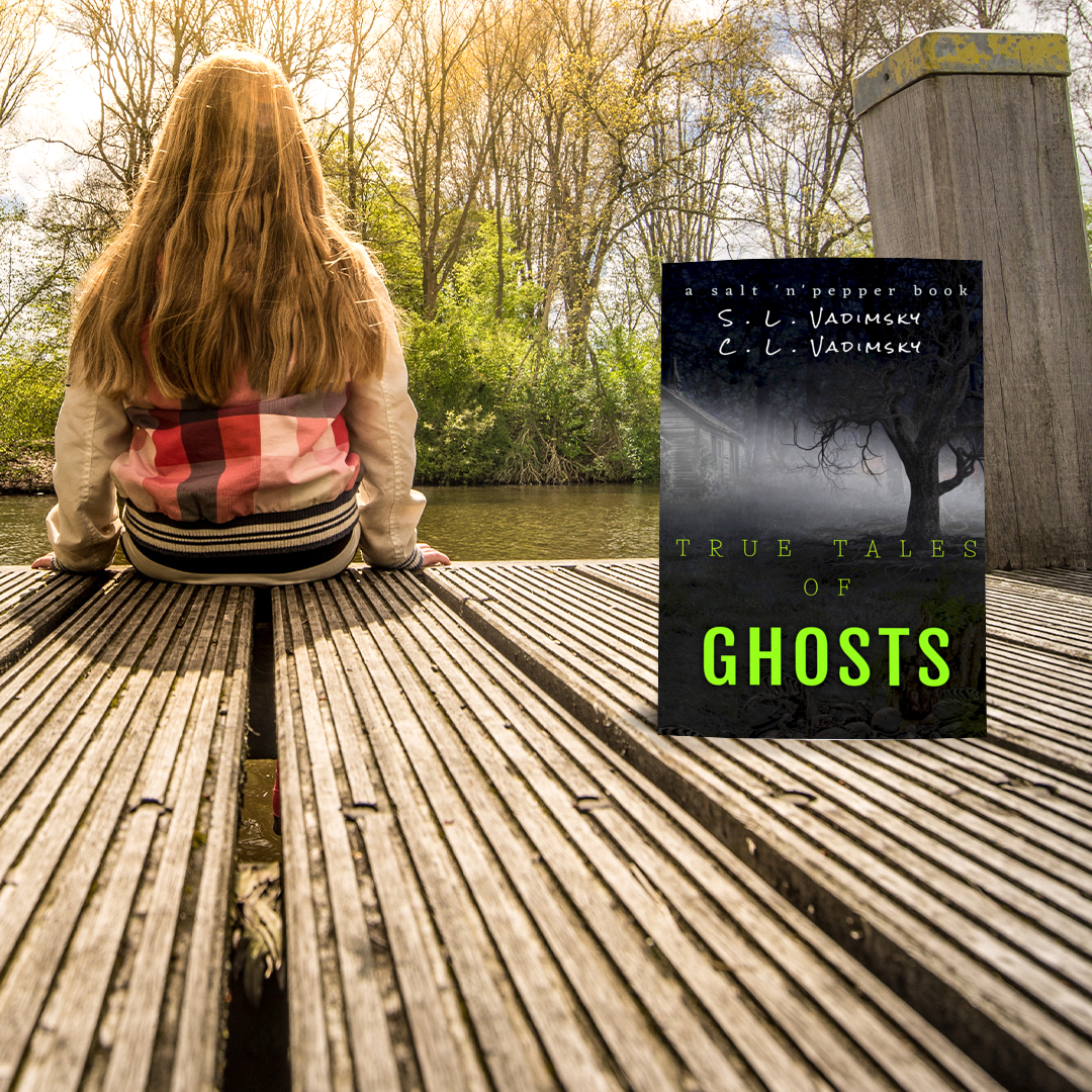 girl with long hair and long sleeve shirt sitting on the edge of a wooden deck over a river or lake, trees in background, book in foregroung, green letters True Tales of Ghosts