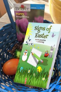 Easter basket holds an egg, a packet of flower seeds, and a word puzzle book titled with text: Signs of Easter